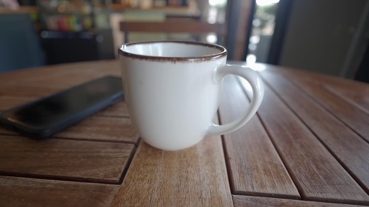 Coffee cup and phone on wooden table