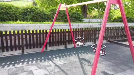 two empty swings are swinging in playground