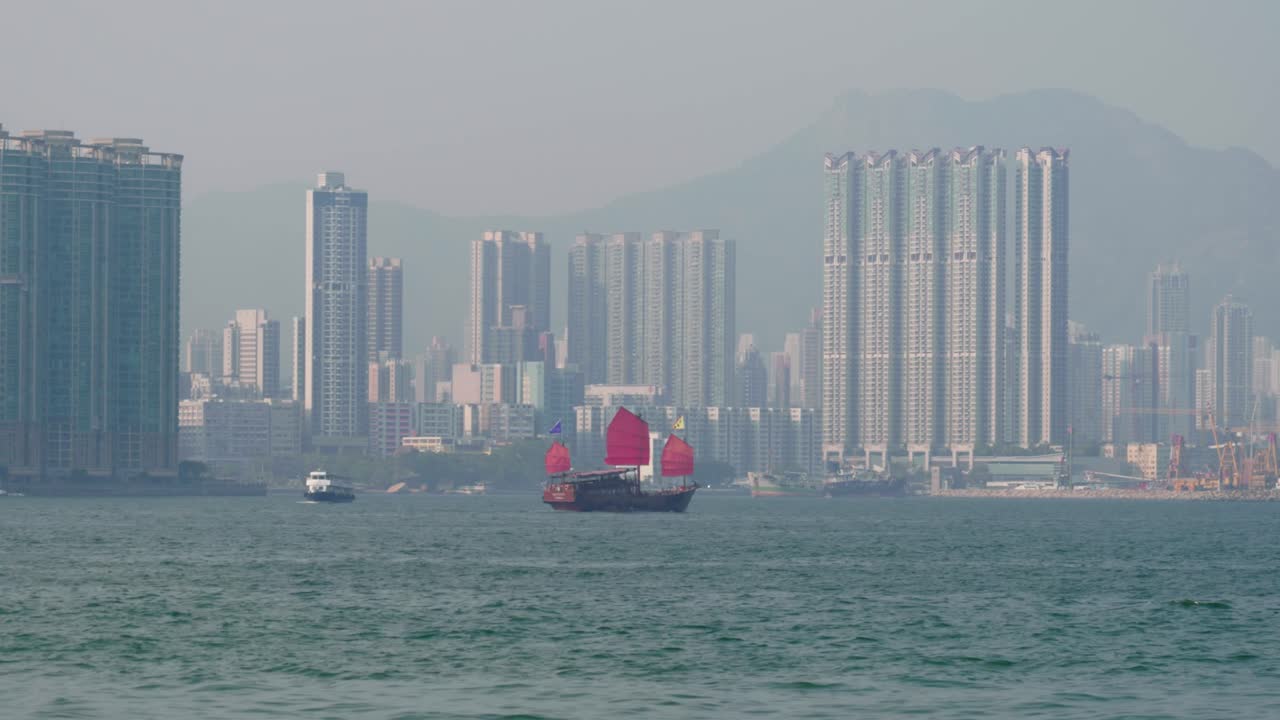 Vista panoramica di una crociera Duckling che naviga attraverso il Victoria Harbour nel centro di Hong Kong in una giornata di sole, con lo skyline sullo sfondo