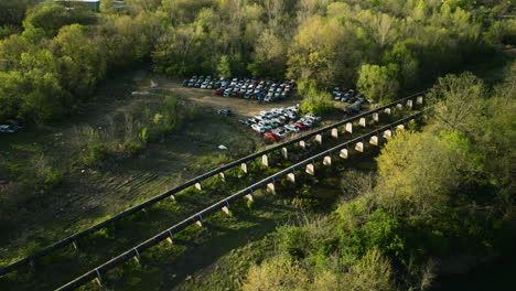 a junkyard with rows of cars in fayetteville, ar, surrounded by lush greenery, aerial view