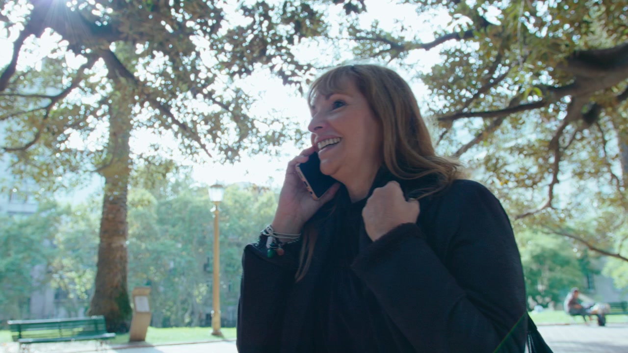 Mature Woman Calling on Mobile Phone during Walk in the Park