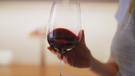la mano de la mujer gira el elegante vaso con vino rojo caro