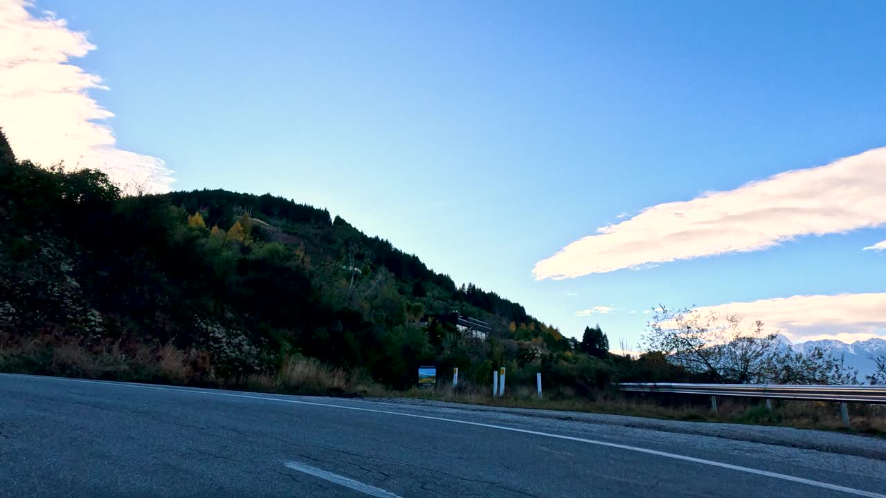 Vehicle drives winding mountain road with lake views, natural landscape, daylight, smooth forward camera motion