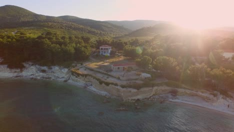 Aerial:-Small-fishing-town-with-Greek-flag-on-Samos-island,-Greece