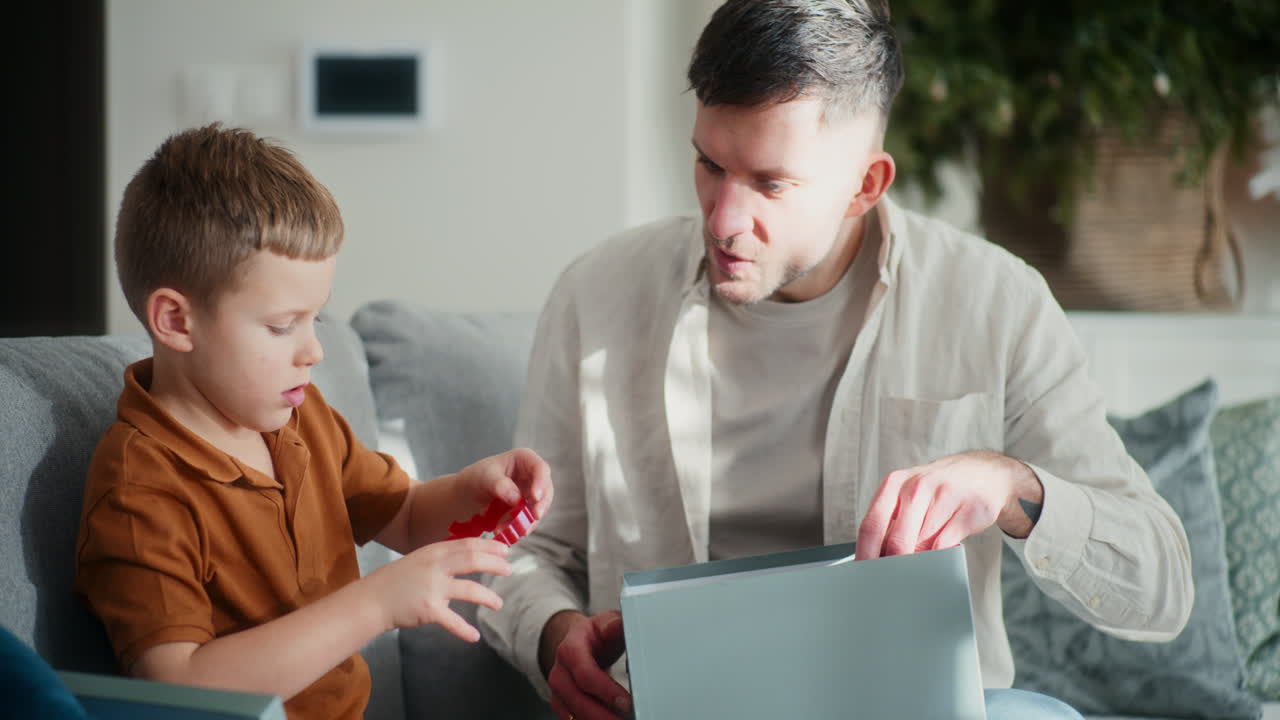 el niño y su padre sacan las decoraciones de navidad de una caja.