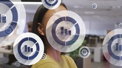 Animation-of-bar-graph-icons-floating-against-biracial-woman-smiling-at-office