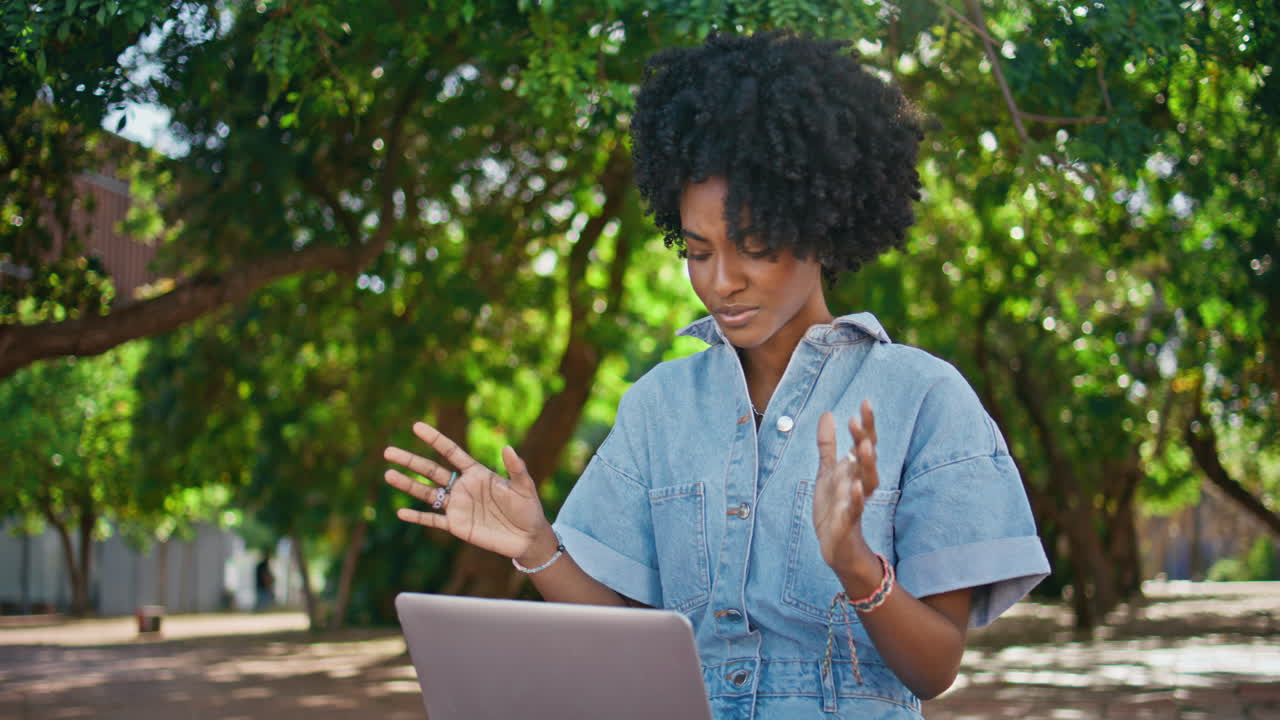 Girl freelancer talking online looking laptop web camera on sunny nature closeup