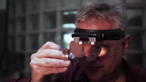 old man inspecting an expensive big gold ring with stones