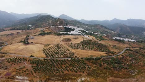 Smooth-aerial-shot-approaching-traditional-white-houses-town-and-a-medieval-castle-on-top-of-a-mountain