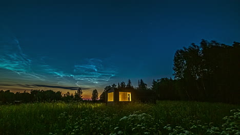 Nightly-timelapse-with-idyllic-cabin-in-grassy-field-and-silky-clouds-in-sky,-remote-tiny-cottage