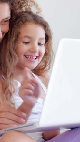 madre y hija felices usando una computadora portátil