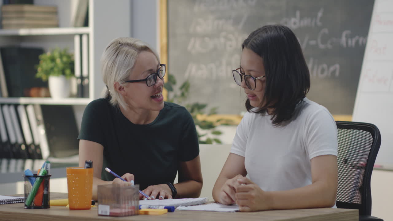 Teacher Tutoring Student in Classroom