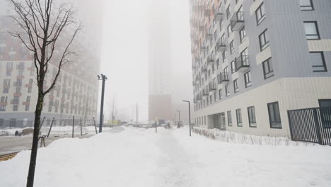 snowy cityscape in fog with apartment buildings