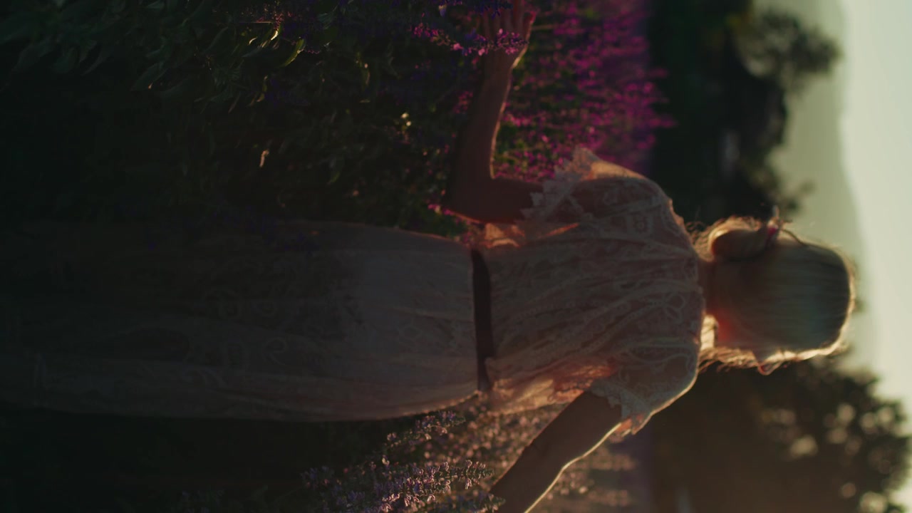 Giovane donna che cammina in un campo di lavanda al tramonto