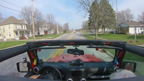 pov while a white haired couple are driving thru a rural small town in the midwest past the henry county court house and high school in cambridge, illinois