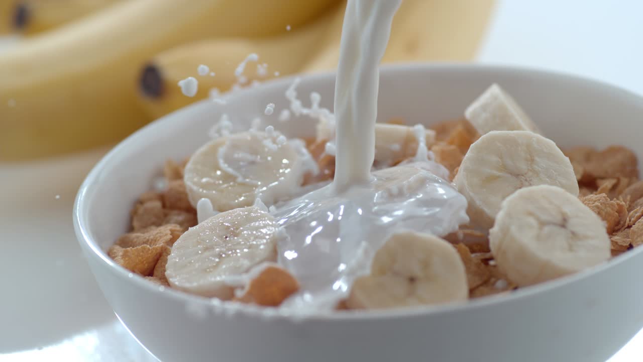 우유가 느린 동작으로 시리얼과 바나나의 그에 부어집니다.