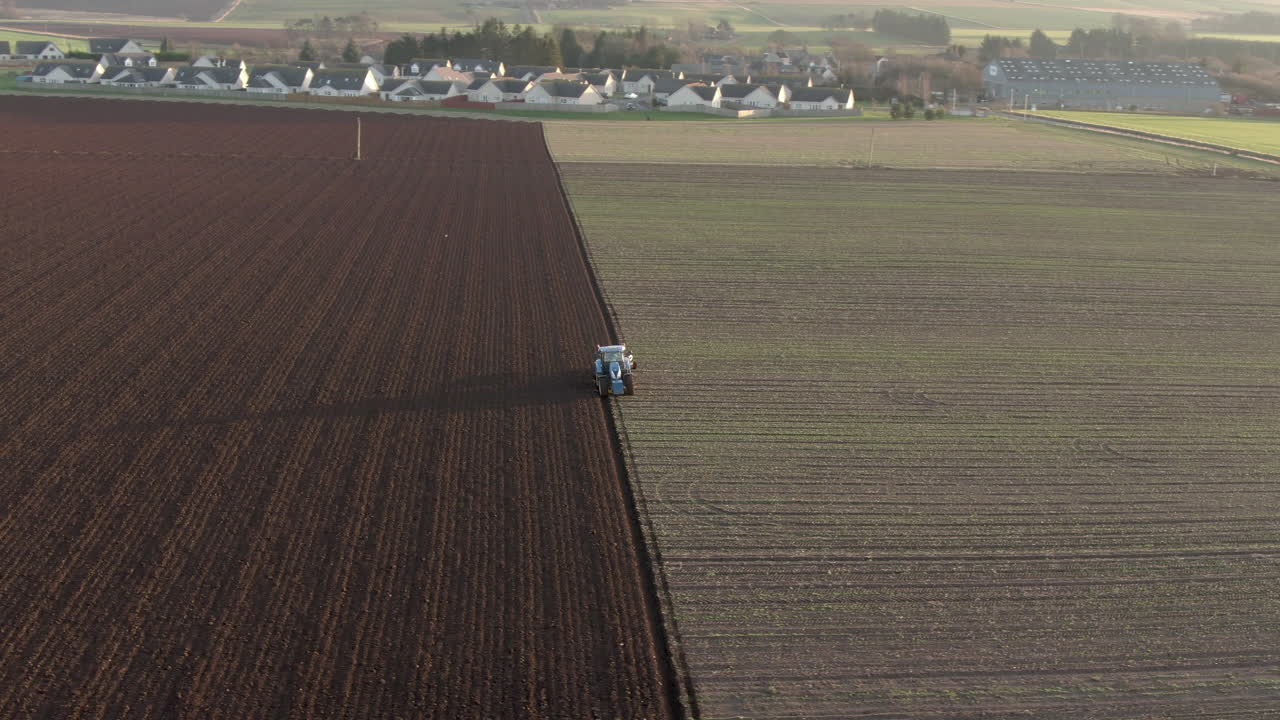 Vista aerea di un trattore agricolo che ara un campo ad Aberdeenshire in una giornata di sole, Scozia