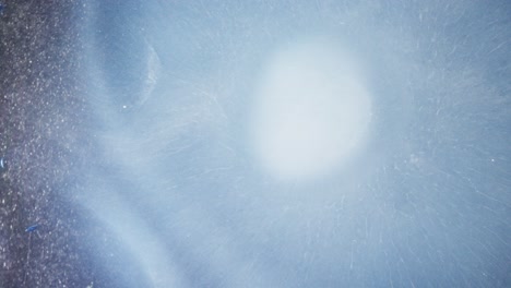 mystical burst of white ink in blue liquid, abstract macro with dreamy texture