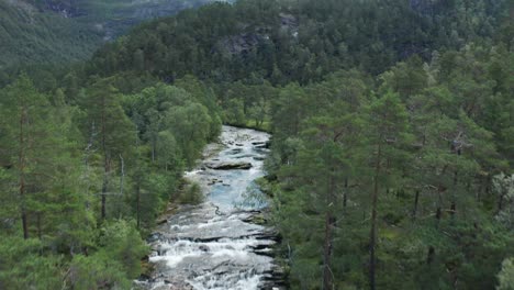 Antena-De-Una-Cascada-Brillante-En-El-área-Protegida-Que-Se-Inclina-Hacia-Arriba-Para-Revelar-Montañas-Y-Valles