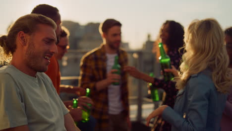 happy people enjoying party with beer outdoors. friends dancing at rooftop party