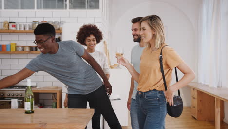 couple greeting friends arriving for dinner party at home with wine