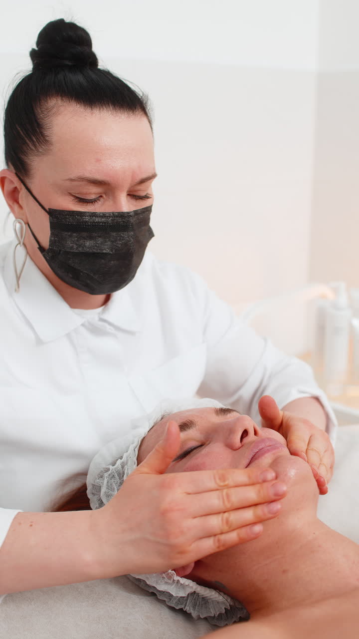 Cosmetologist applying special moisturizing cream scrub peeling face of pretty caucasian woman girl