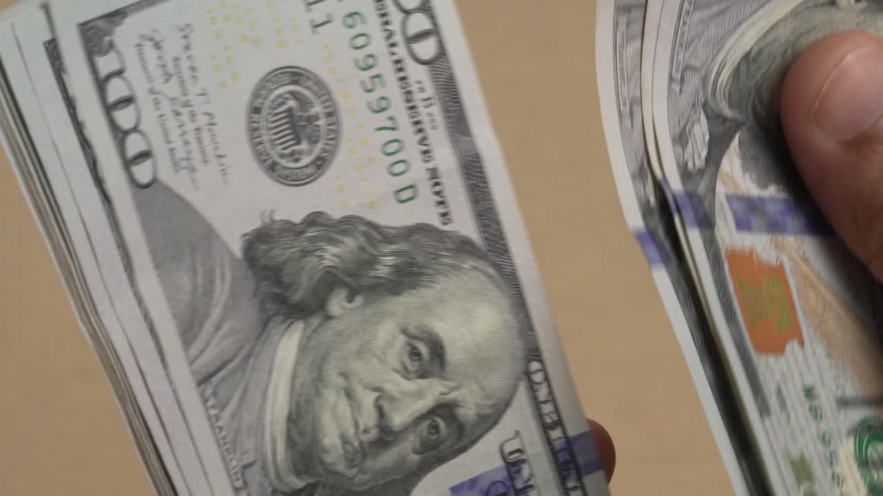 Primissimo piano di mani che contano una pila di banconote da cento dollari USA, concetto di transazione finanziaria in contanti, video 4K