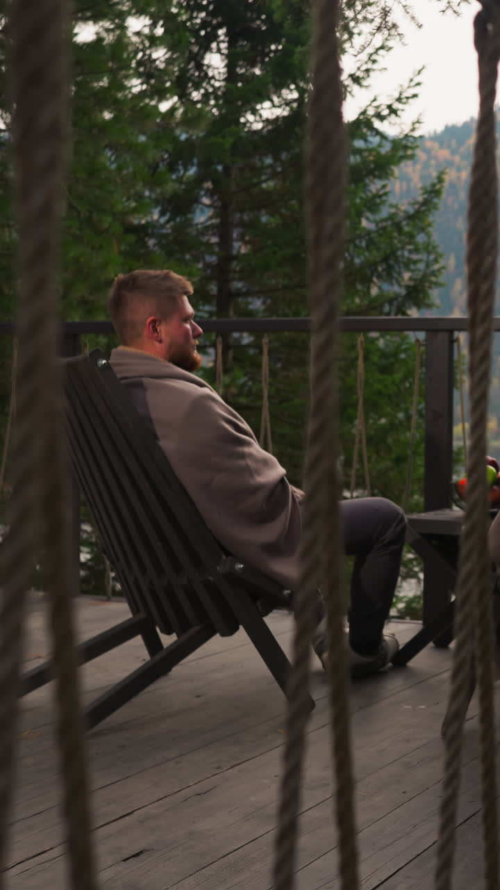 Husband and wife in blankets in glamping house at twilight. Couple spends vacation merging with nature in country cottage. Honeymoon by mountains in autumn