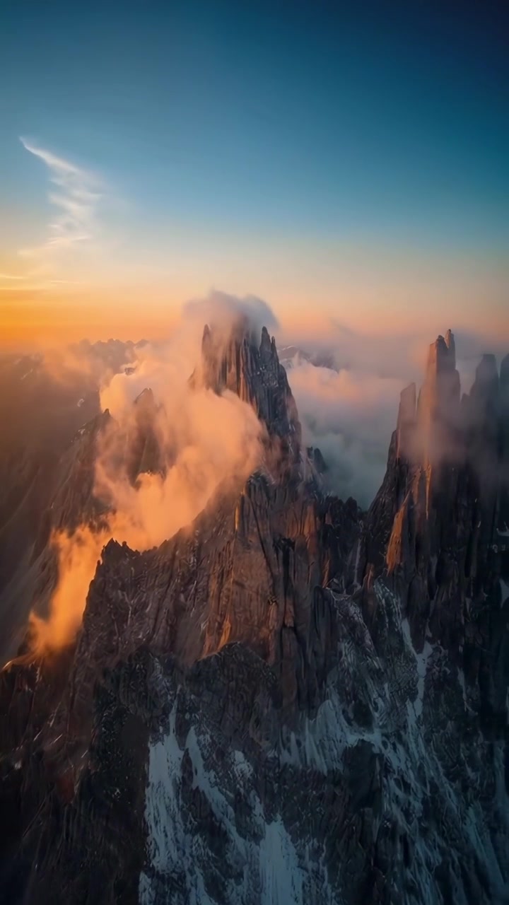 Vista aérea de majestuosos picos de montaña con nubes a la hora dorada