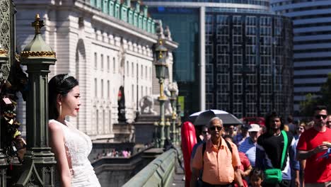 woman posing on bridge with crowd passing by