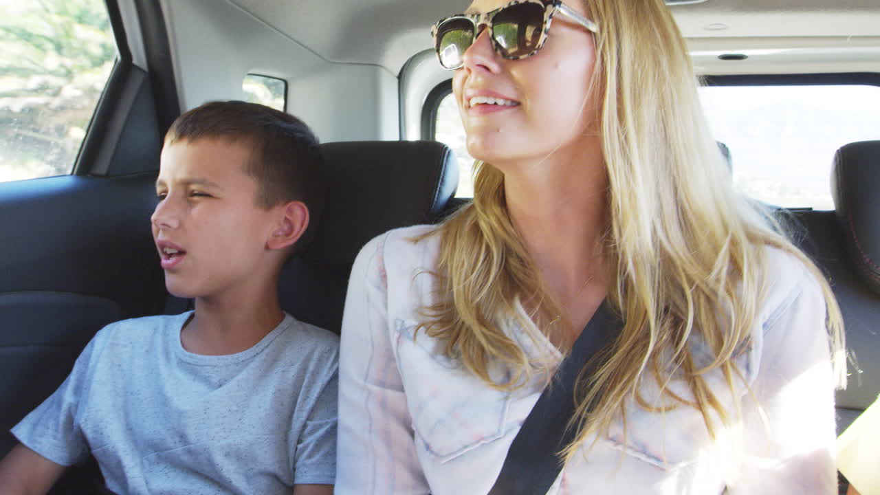 두 자녀와 함께 차 뒷좌석에서 여행하는 어머니