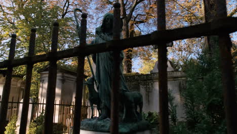 toma ascendente de una hermosa estatua tras las rejas en el cementerio pere lachaise