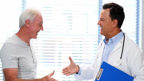 doctor and senior man smiling while having discussion over a report