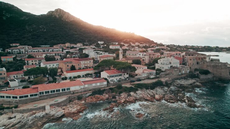 Drone, plano aéreo ao pôr do sol, cidade costeira, Algajola, França, Córsega.