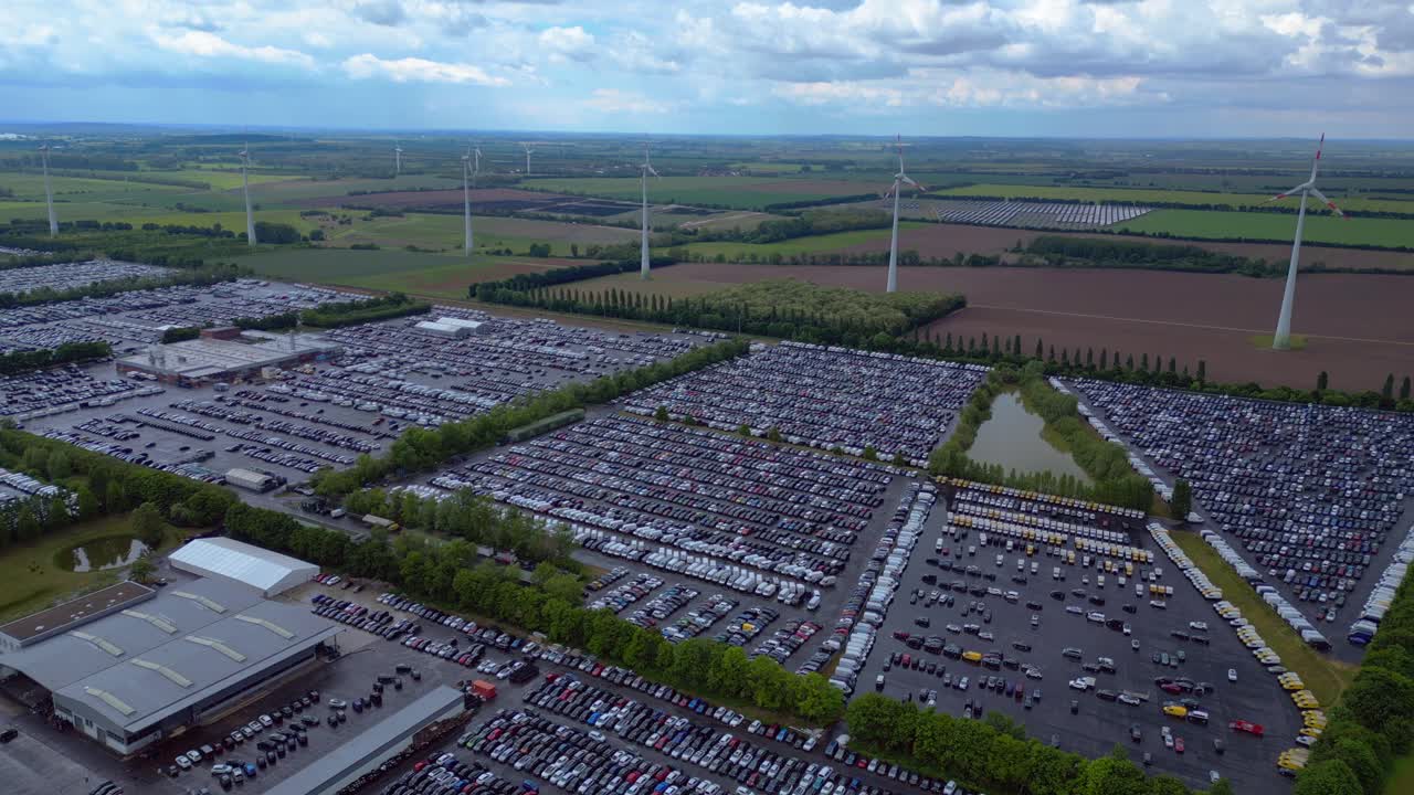 large parking lot full of cars near a wind farm and countryside in Germany. Breathtaking aerial view flight drone top down Above view