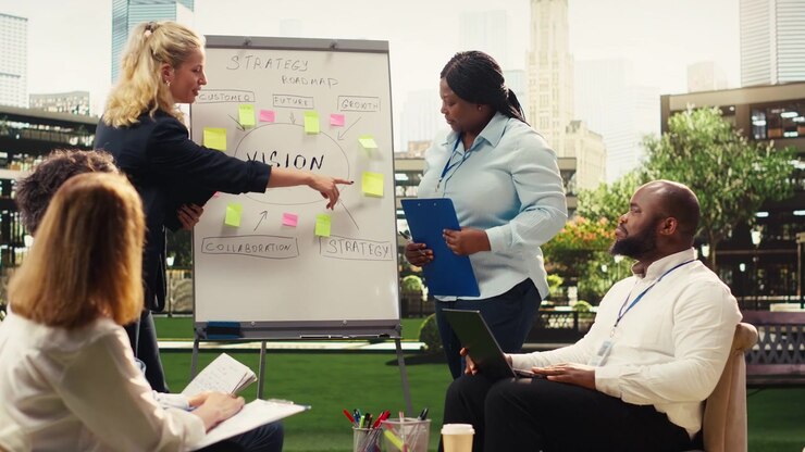 Diverse coworkers leading action plan discussion with whiteboard