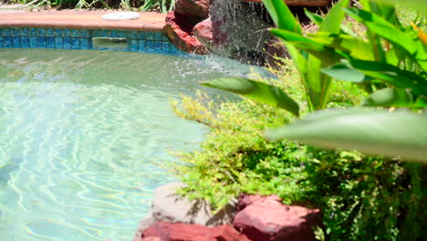 Water-cascades-across-artificial-rocks-into-outdoor-tropical-pool