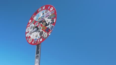 señal de tráfico llena de pegatinas sacudiendo en el desierto cielo azul