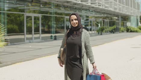 pretty muslim woman swinging shopping bags on warm summer day.