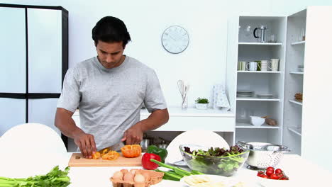 hombre feliz cortando verduras
