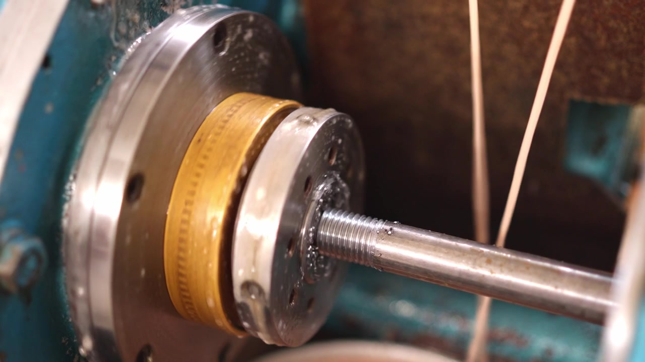 Máquina laminadora de roscas creando roscas en una barra metálica
