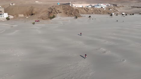 aerial spinning shot from the beautiful beach caleta vidal in peru with people running in the sand and view of the city and the sea with calm waves on a cloudless summer day