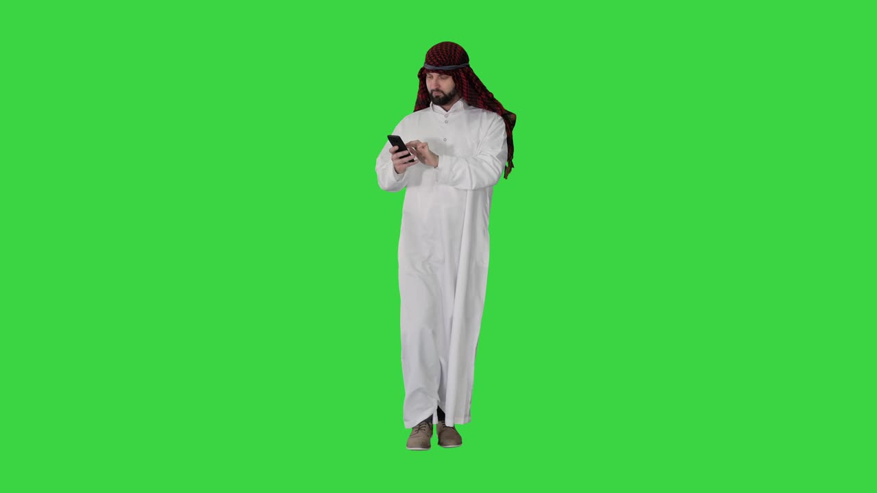 Arab sheikh wearing keffiyeh receiving grate news on the phone on a Green Screen, Chroma Key