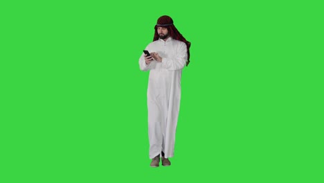 ein arabischer scheich, der eine keffiyeh trägt, empfängt grate-nachrichten am telefon auf einem grünen bildschirm, chroma-taste