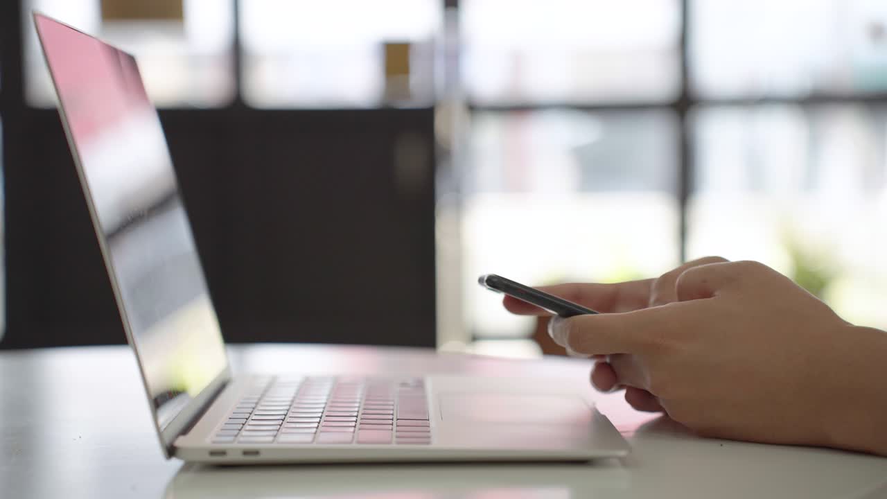 hombre de negocios de cerca escribiendo teléfono inteligente quedarse trabajando con computadora portátil en la oficina.