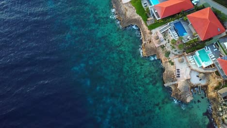 overhead dolly-in aerial view of mansions on the shore of jan thiel beach, curacao, dutch caribbean island of the caribbean