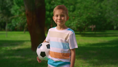 little kid with ball smiling on nature. portrait of cute sportsman in park.