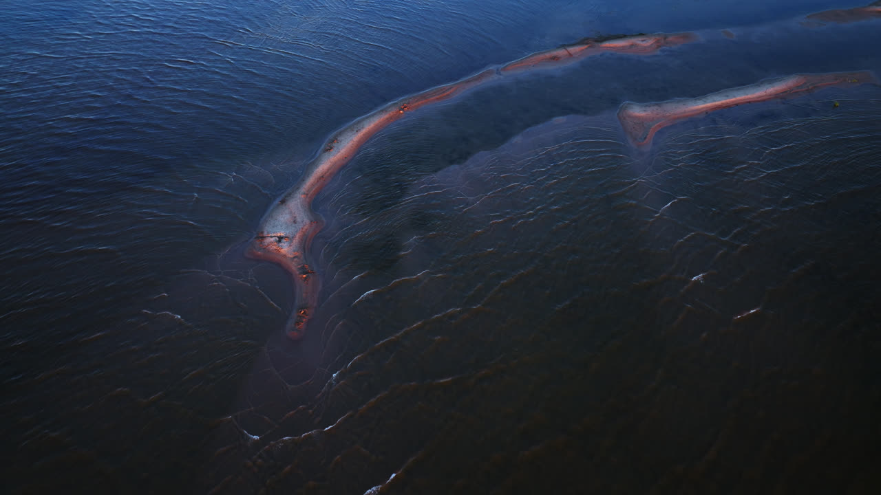 Aerial view following a sand bank in calm waters of Kalajoki, sunset in Finland