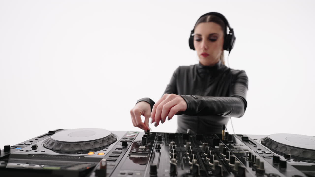 una dj femenina en un traje de cuero negro mezclando música en un mezclador con un tocadiscos