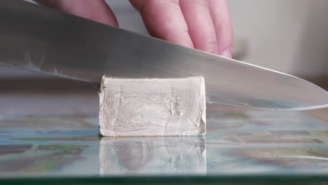 sharp-knife-slice-yeast-cube-on-cutting-board-in-slow-motion-close-up